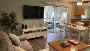A living room with a sofa, a coffee table, a TV, and a dining area with chairs and a table. - Cute, spacious 2 BR 2 Full BA condo minutes from the beaches (Largo)