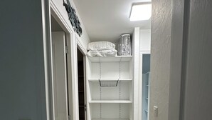 A narrow hallway leading to a closet with white shelves and a hanging rack. - Apartment T3 in Carnac plage (Carnac)