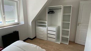 A bedroom with a lofted sleeping area, a walk-in closet, and a window with blinds. - Apartment T3 in Carnac plage (Carnac)