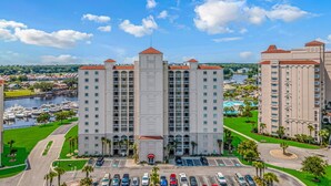 A multi-story hotel with a central tower, parking lot, and marina in the background. - Intercostal Waterway Hotel Style Room -- 5 min from the beach! (North Myrtle Beach)