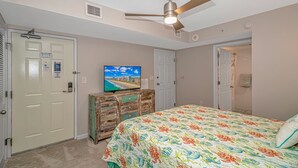 A bedroom with a bed, a television on a dresser, a ceiling fan, and a door. - Intercostal Waterway Hotel Style Room -- 5 min from the beach! (North Myrtle Beach)
