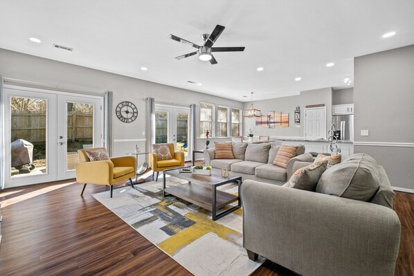 A spacious living room with a modern design, featuring a sofa set, a coffee table, and a ceiling fan.