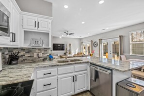 A modern kitchen with white cabinets, a granite countertop, a built-in oven, and a dishwasher.