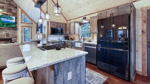 A modern kitchen with a large island, built-in appliances, and a rustic wooden ceiling.