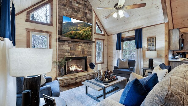A cozy cabin interior with a fireplace, wooden walls, and a comfortable seating area.