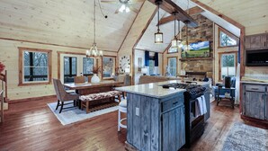 A spacious kitchen with a large island, wooden beams, and a stone accent wall.