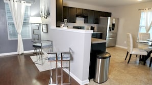 A modern kitchen with dark cabinets, stainless steel appliances, and a small island.
