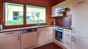 A kitchen with wooden cabinets, a dishwasher, a stove, and a window overlooking a garden. - 2 bedroom cozy home in Boiensdorf (Boiensdorf)