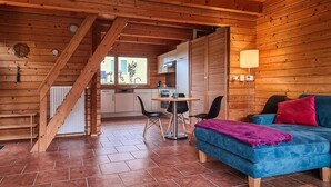 A cozy log cabin interior with a dining area, kitchen, and a blue sofa with a purple throw blanket. - 2 bedroom cozy home in Boiensdorf (Boiensdorf)