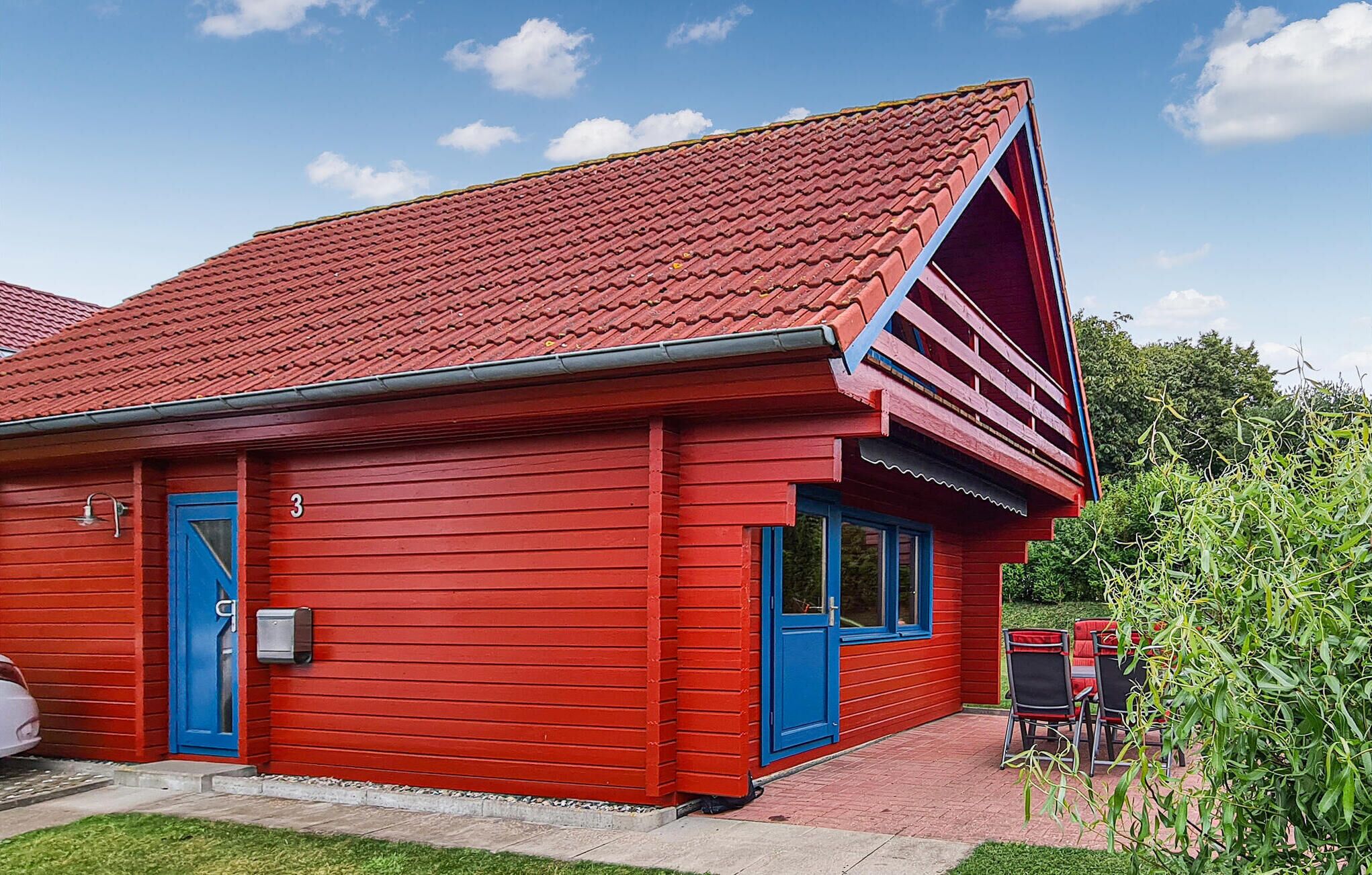 A red wooden house with a sloped roof and blue doors.