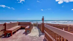 A wooden boardwalk leading to the beach with benches and a railing.