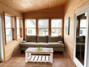 A cozy room with a wooden ceiling, a beige sofa, and a white coffee table.
