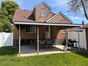 A house with a covered patio, a brick exterior, and a chimney. - Charming Brick Home with bonus space fenced yard (Spokane)