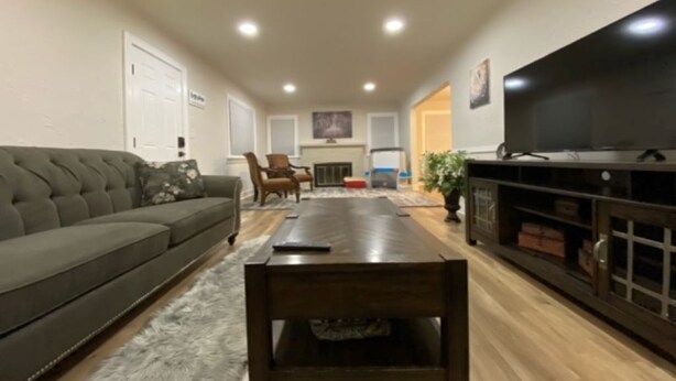 A living room with a dark-colored sofa, a wooden coffee table, a television on a stand, and a fireplace in the background.