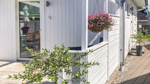 Un edificio de madera blanca con puerta de vidrio y una cesta de flores colgante.