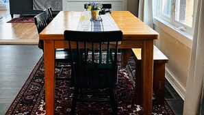 A dining area with a wooden table, black chairs, and a patterned rug.