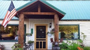A rustic building with a wooden porch, an American flag, and a mailbox labeled "OFFICE".