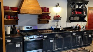 A kitchen with wooden shelves, a stove, and a sink.
