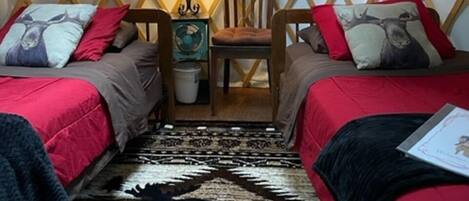 A cozy yurt interior with two beds, a central seating area, and a decorative tapestry.