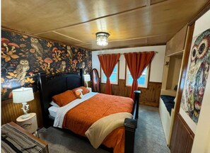 Relax in a classic bedroom with a large bed, vibrant floral wallpaper, and a wooden nightstand.