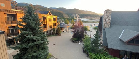 Un bâtiment à la façade en bois, doté d’une cour pavée et surplombant un paysage montagneux.