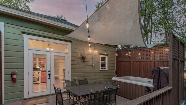 A patio with a table and chairs, a hot tub, and a covered area with string lights.