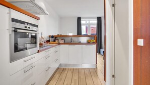 A modern kitchen with white cabinets, a built-in oven, and a wooden countertop.