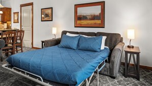 Une pièce comprenant un lit, une chaise, une table et un tableau accroché au mur.