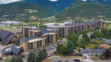 A residential area with multi-story buildings, a parking lot, and a mountainous backdrop.