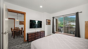 Une chambre avec un grand lit, une télévision, une commode et un balcon avec vue.
