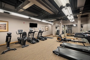 A gym with various exercise equipment including treadmills, stationary bikes, and elliptical machines.