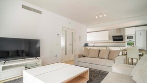 Ein modernes Wohnzimmer mit einem Flachbildfernseher, einem weißen Sofa und einem Couchtisch.