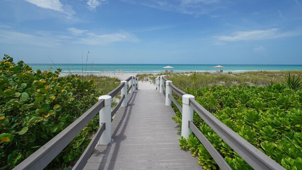 A wooden pathway leading to a beach with a clear sky. - Stunning 2 BR Condo views of the Gulf and Lake (Longboat Key)