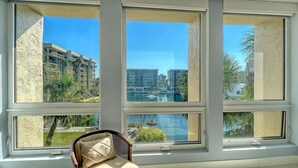 A room with a large window overlooking a building complex and a body of water. - Stunning 2 BR Condo views of the Gulf and Lake (Longboat Key)