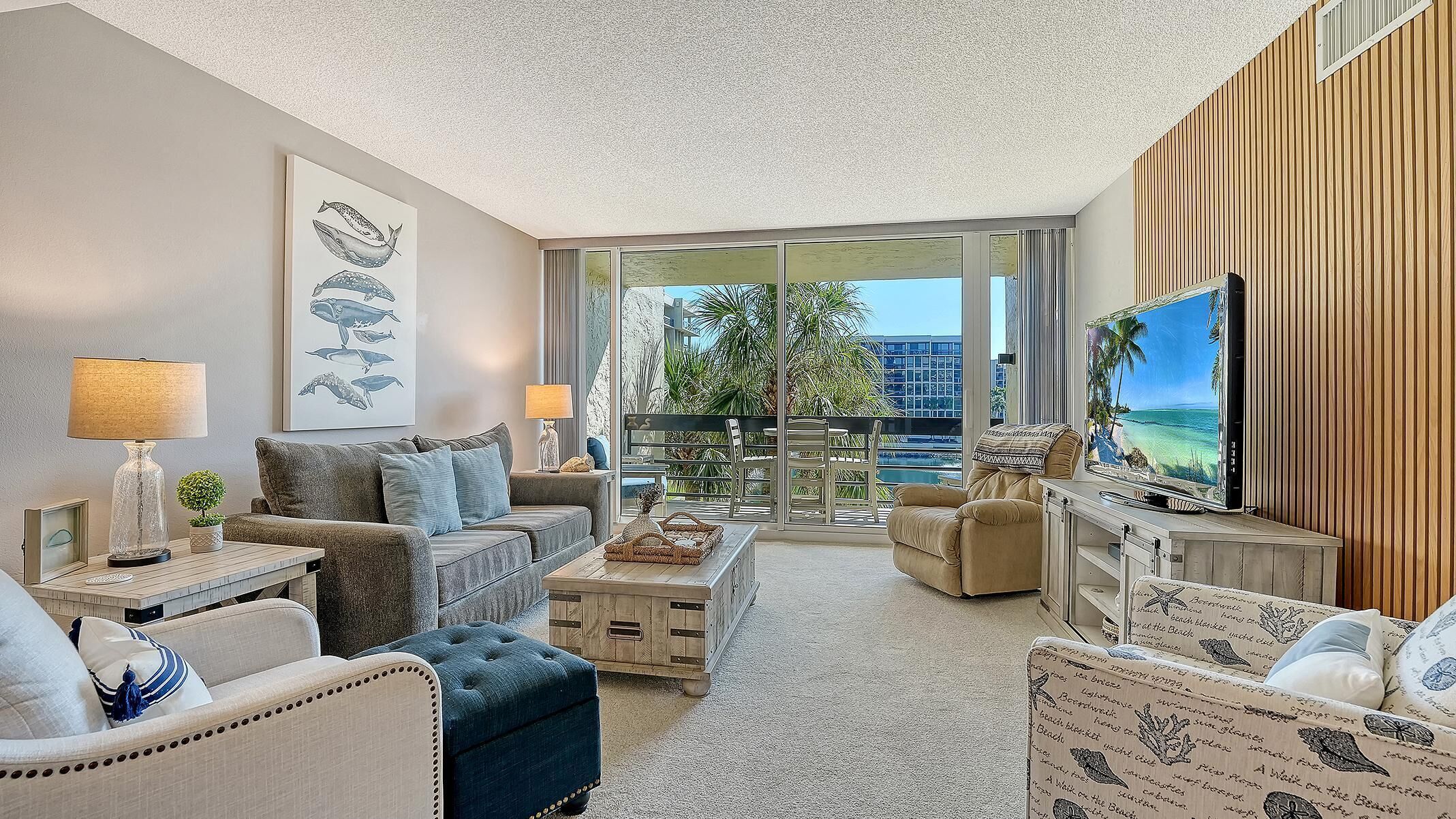 A modern living room with a balcony, a large TV, and a view of the city.