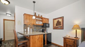 Une cuisine compacte avec des meubles en bois, un four à micro-ondes et un petit réfrigérateur.
