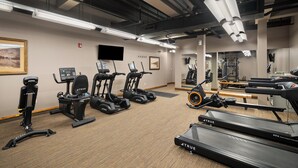 Une salle de sport équipée de divers appareils d’exercice, notamment des tapis de course, des vélos d’appartement et des appareils de musculation elliptique.