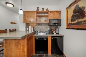 A kitchen with wooden cabinets, a built-in dishwasher, a coffee maker, and a television.