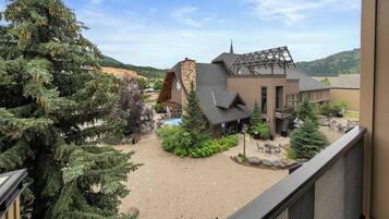 Un resort con un edificio de piedra, mobiliario exterior y vistas al bosque circundante.
