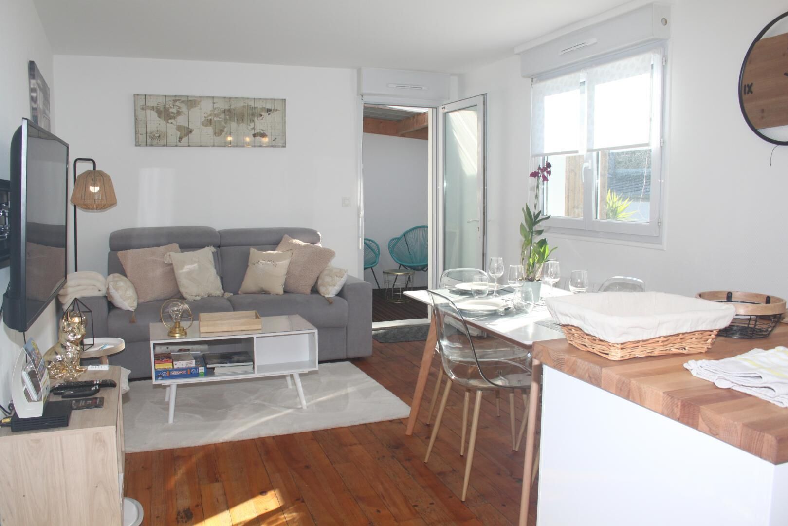 A modern living room with a grey sofa, a coffee table, and a dining area with a table set for four.