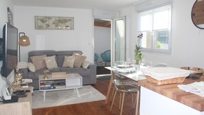 Una sala moderna con un sofá gris, una mesa de centro y un comedor con una mesa dispuesta para cuatro.