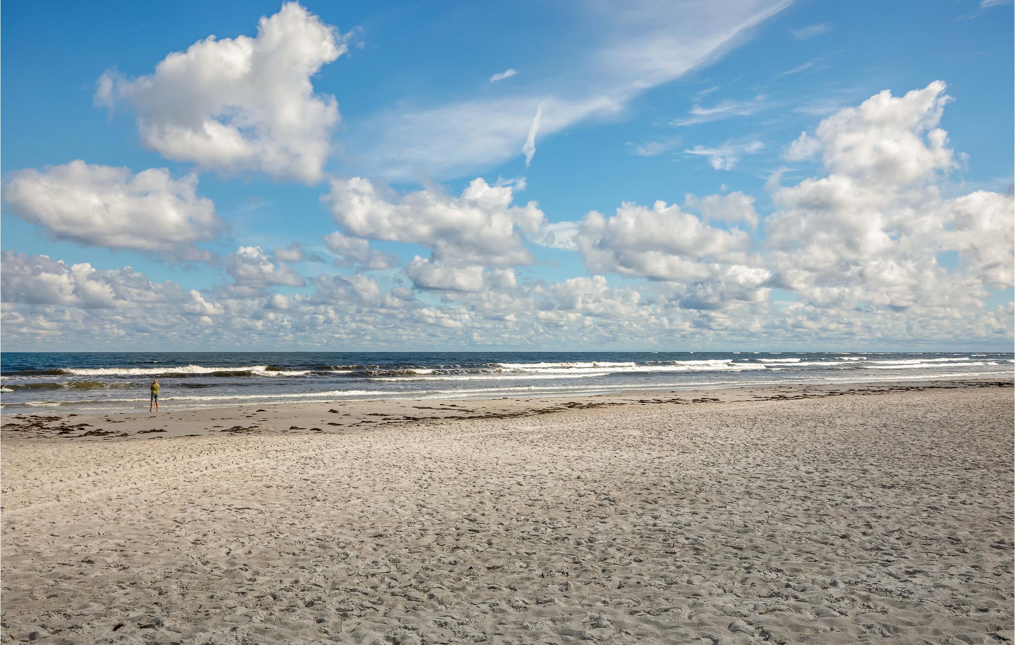 A beach with a wide sandy shore and waves crashing onto the beach.