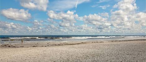 A beach with a wide sandy shore and waves crashing onto the beach.