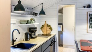 A kitchen with a sink, coffee maker, and shelves with dishes. - 1 bedroom lovely home in Nexø (Nexø)