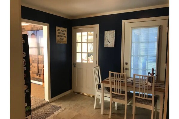 Cozy retreat with a comfortable seating area, featuring a table and chairs, a picture on the wall, and a window with blinds.