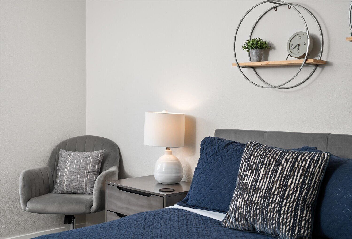 Cozy modern bedroom with navy bedding, warm lighting, and stylish decor