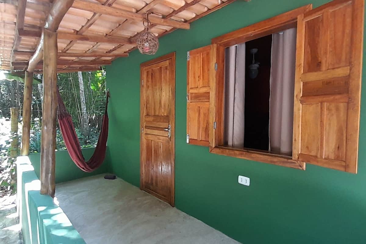 Une pièce avec un mur vert, des portes en bois et une fenêtre avec des volets en bois.