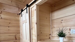 A wooden interior with a sliding door, a small plant on a counter, and a power outlet.
