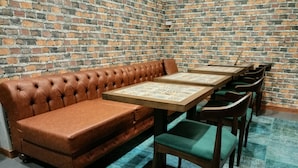 Un rincón con asientos, un sofá de cuero marrón y una mesa de madera con sillas.