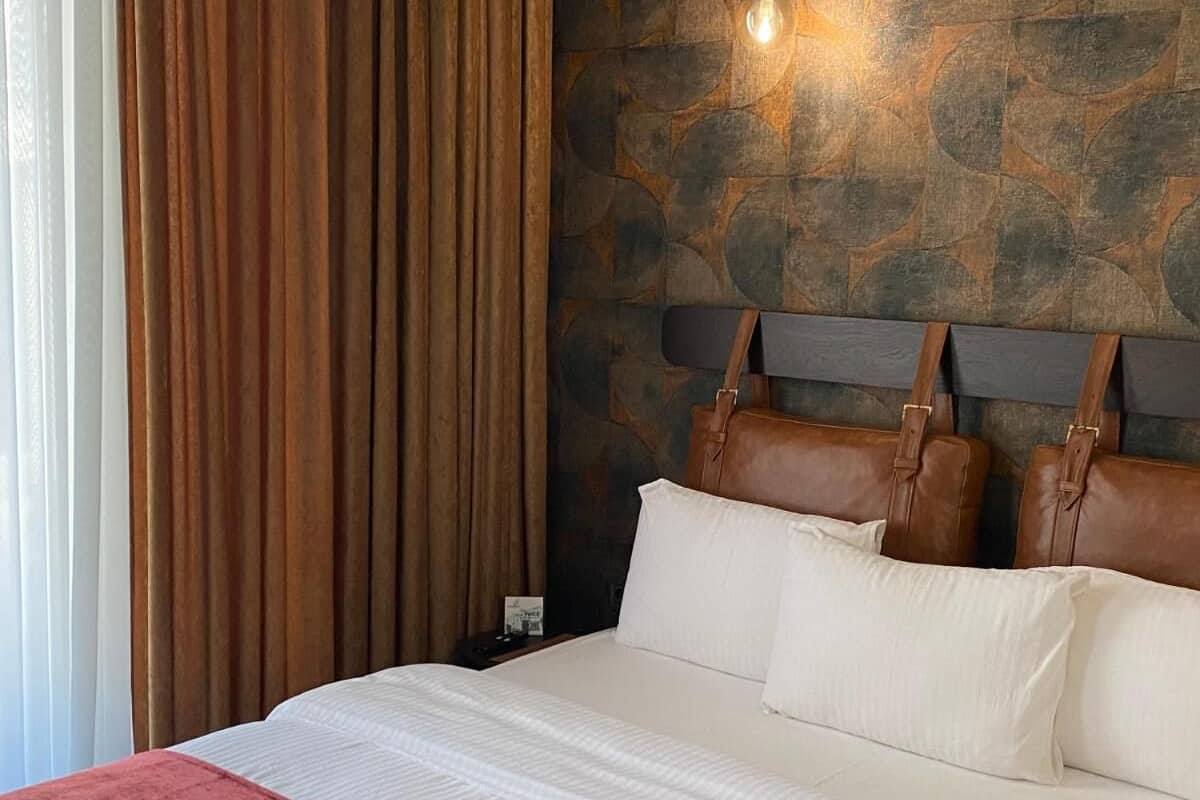 Een bed met hoofdeinde, nachtkastje en een muur met steenmotief.